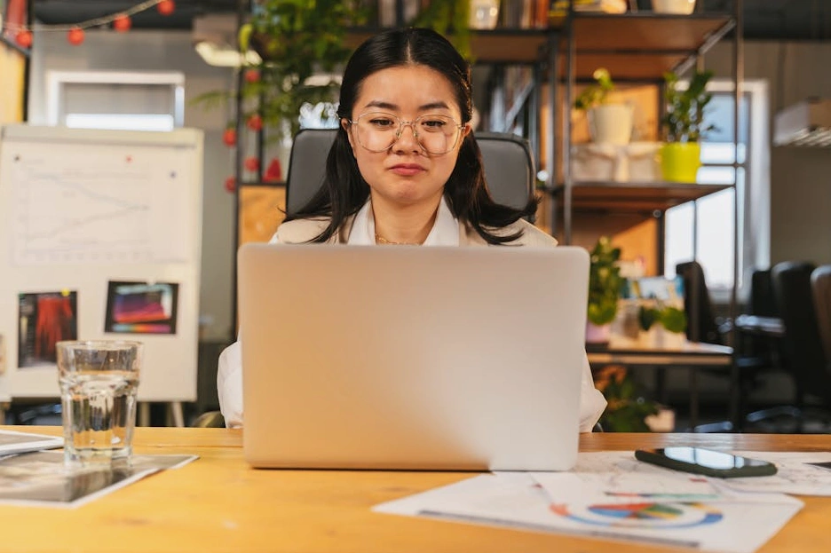 Osoba pracująca przy laptopie i analizująca wykresy